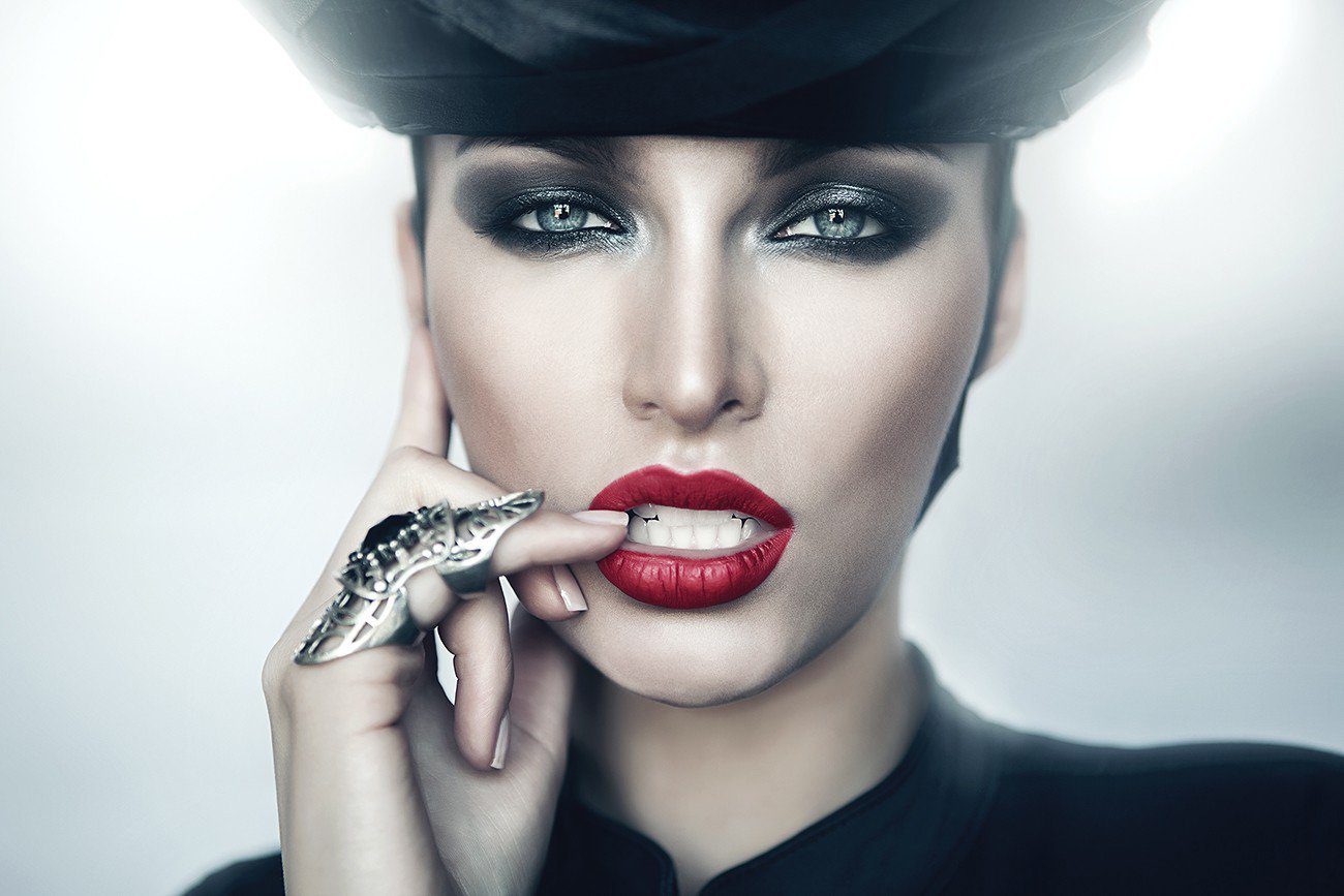 A woman with red lipstick and a black hat.
