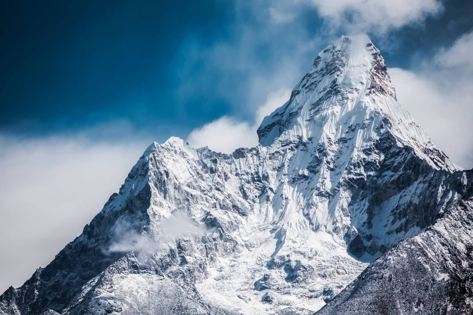 A mountain with snow on it and clouds in the sky.