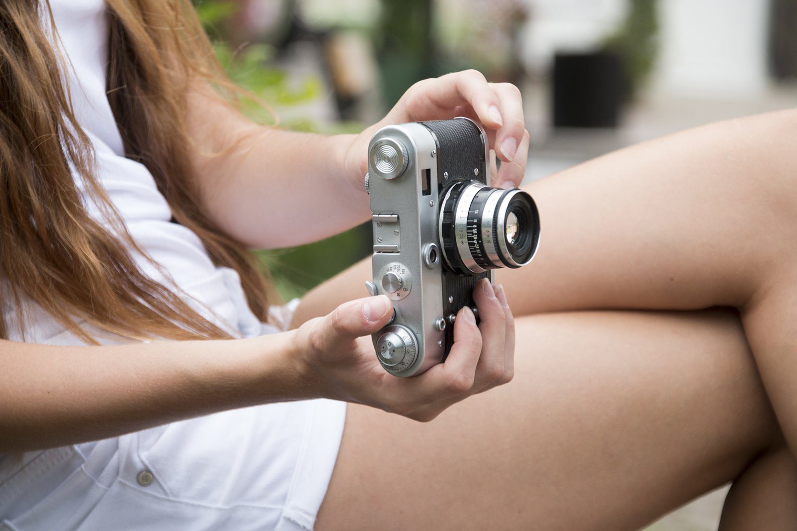 A woman holding an old fashioned camera in her hands.